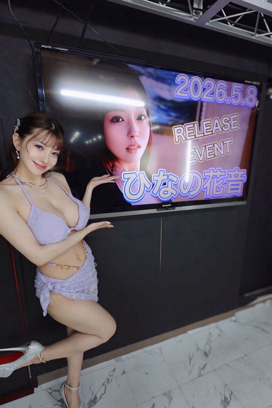 リリースイベントの会場で、告知の画面の前に立つタレント