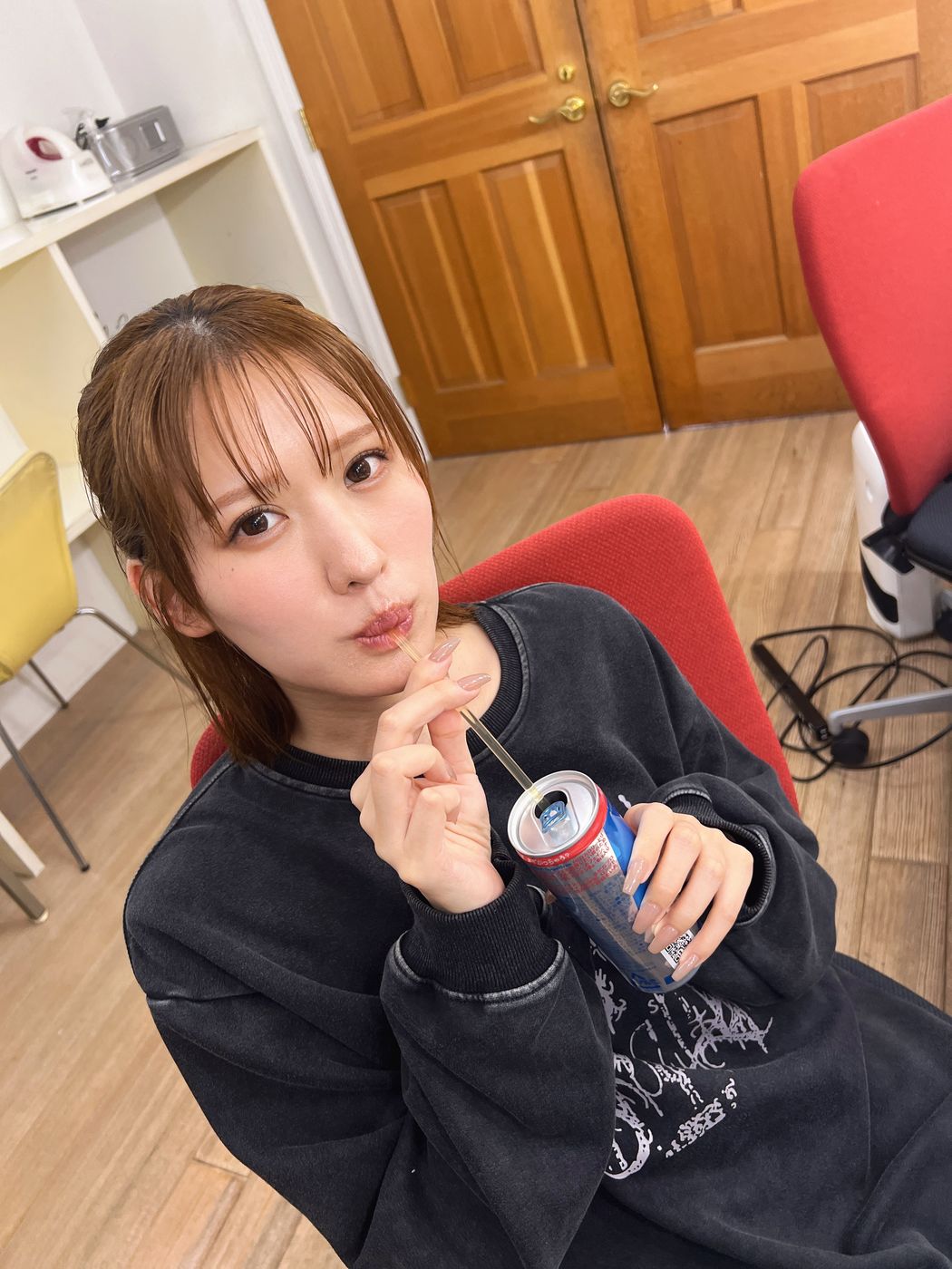 撮影の休憩中、椅子に座って飲み物を飲むタレント