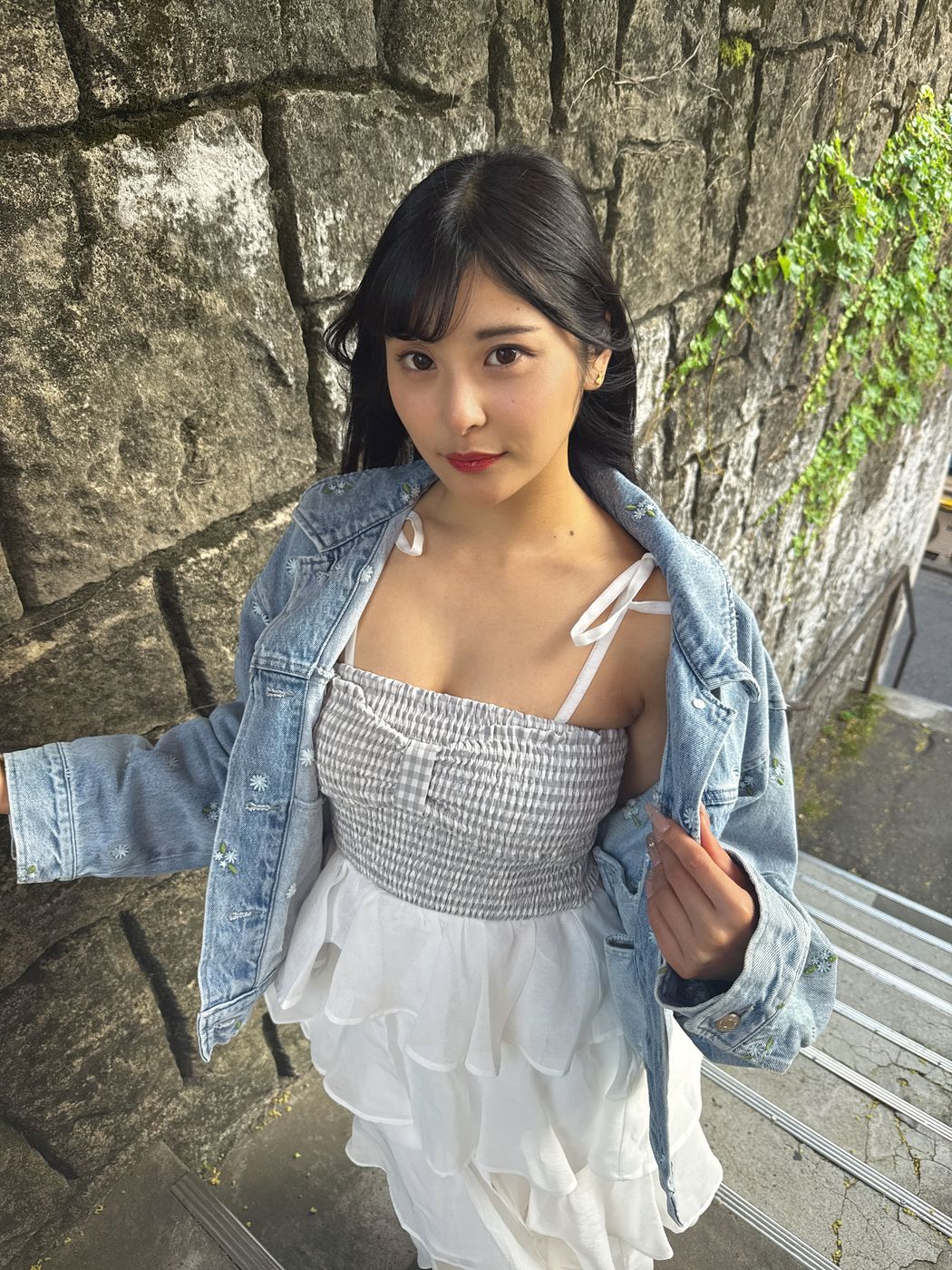 屋外の石垣の前で撮影したSNS用の写真