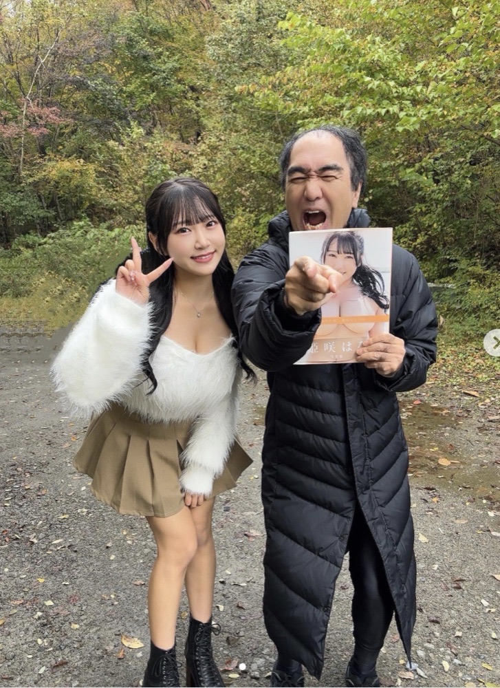 屋外ロケで、写真集を持って並ぶタレント